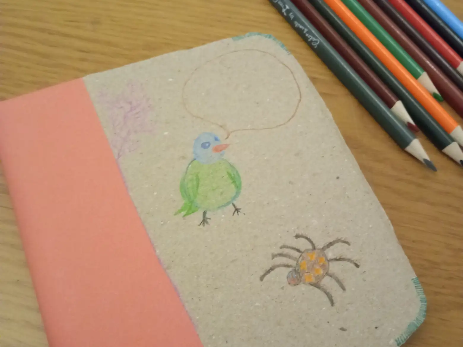 Foto de un libro hecho con cartón, cerca de unos lápices de colores